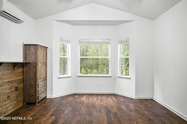 unfurnished bedroom featuring vaulted ceiling, dark wood-type flooring, a wall mounted AC, and a textured ceiling