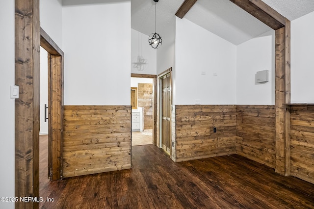 interior space featuring a textured ceiling, dark hardwood / wood-style floors, vaulted ceiling with beams, and wood walls