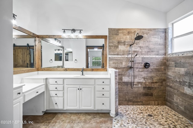 bathroom featuring vanity, a tile shower, and vaulted ceiling