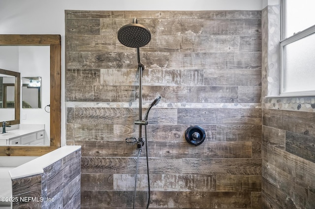 bathroom with a tile shower and vanity