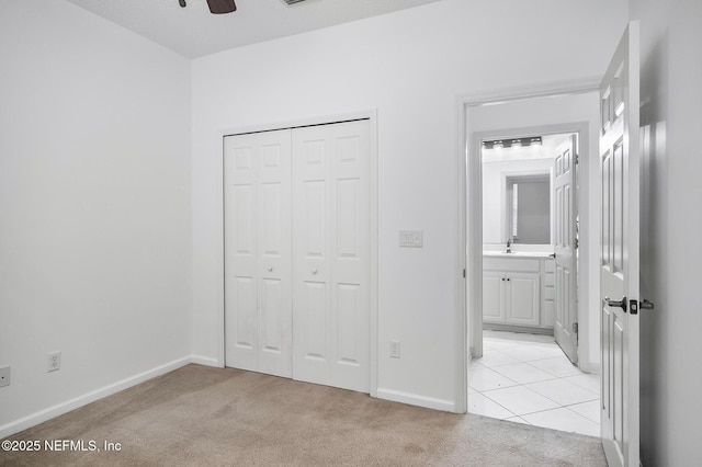 unfurnished bedroom featuring ensuite bathroom, ceiling fan, a closet, light colored carpet, and sink