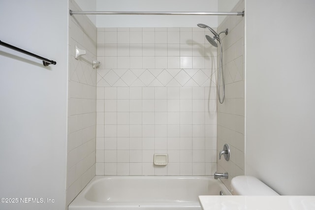 bathroom featuring toilet and tiled shower / bath