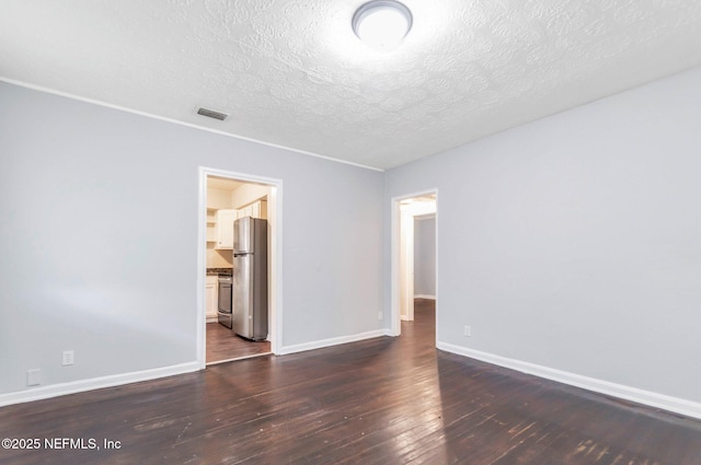 empty room featuring a textured ceiling and dark hardwood / wood-style flooring