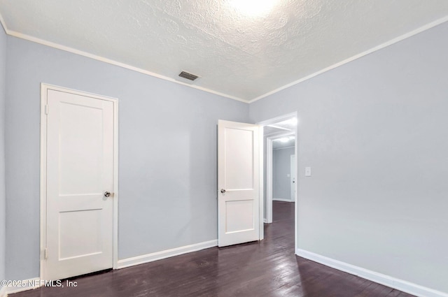 spare room featuring dark wood-type flooring, a textured ceiling, and ornamental molding