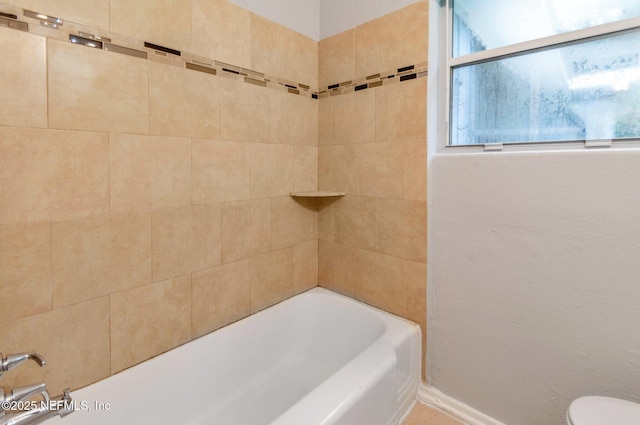 bathroom featuring toilet and tiled shower / bath