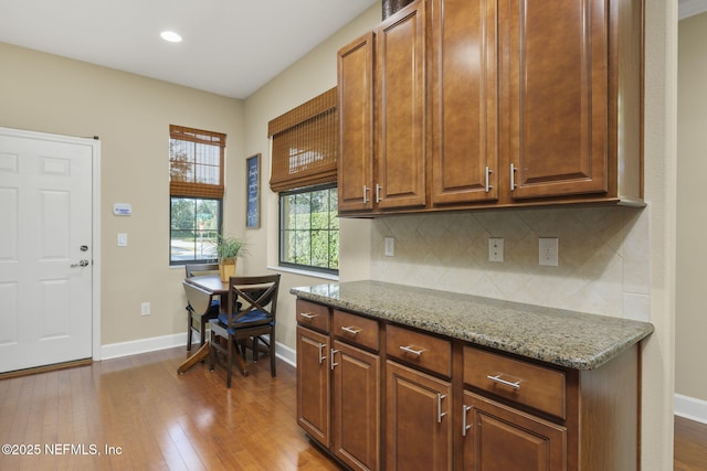 kitchen featuring tasteful backsplash, light stone countertops, and dark hardwood / wood-style flooring