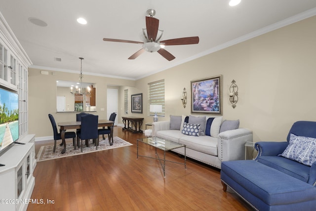 living room with ornamental molding, ceiling fan with notable chandelier, and dark hardwood / wood-style flooring