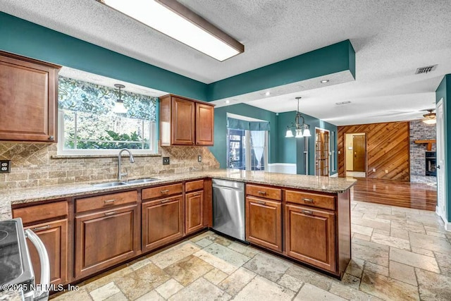 kitchen featuring wood walls, kitchen peninsula, stainless steel appliances, hanging light fixtures, and sink