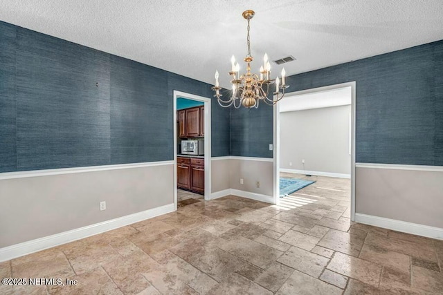 unfurnished dining area featuring a chandelier and a textured ceiling