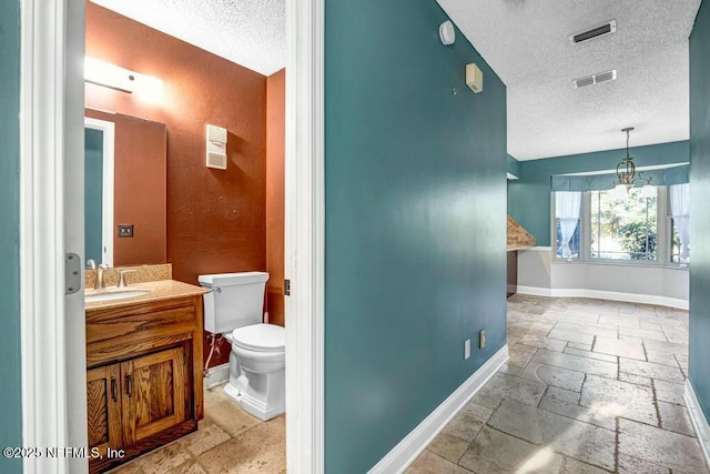 bathroom featuring a textured ceiling, toilet, and vanity