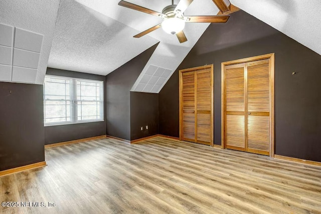 bonus room featuring light wood-type flooring, ceiling fan, lofted ceiling, and a textured ceiling