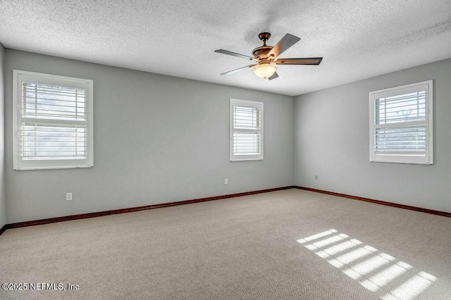 carpeted empty room featuring ceiling fan, plenty of natural light, and a textured ceiling