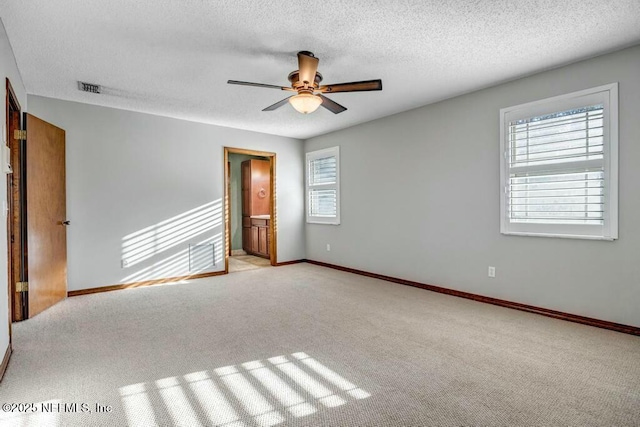 carpeted spare room featuring ceiling fan, a wealth of natural light, and a textured ceiling