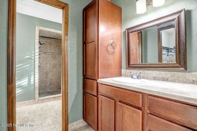 bathroom featuring tiled shower and vanity