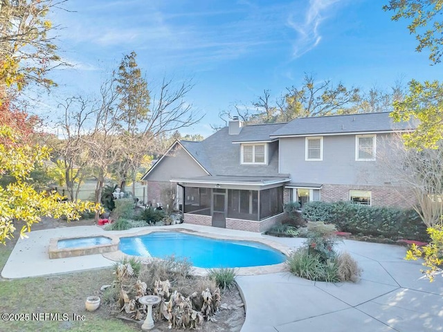 rear view of property with a swimming pool with hot tub, a sunroom, and a patio