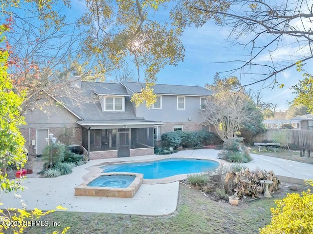 back of house featuring a pool with hot tub, a patio area, and a sunroom