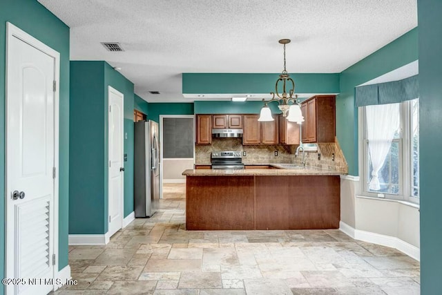 kitchen featuring kitchen peninsula, appliances with stainless steel finishes, backsplash, pendant lighting, and sink