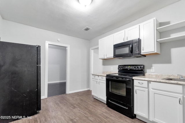 kitchen featuring black appliances, light wood-type flooring, and white cabinetry