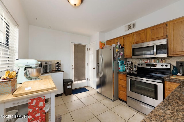 kitchen featuring light tile patterned flooring, stainless steel appliances, and backsplash