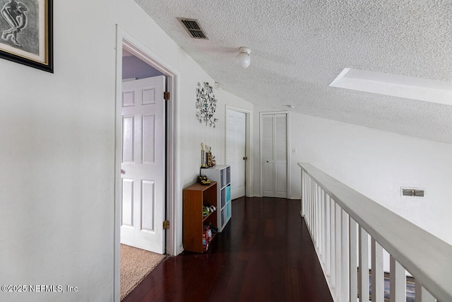 corridor with dark wood-type flooring and a textured ceiling