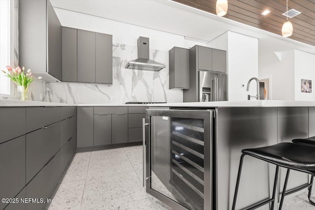 211 Belvedere St, Atlantic Beach, FL 32233 - kitchen featuring gray cabinets, high end refrigerator, wall chimney range hood, dark speckled floor, and beverage cooler