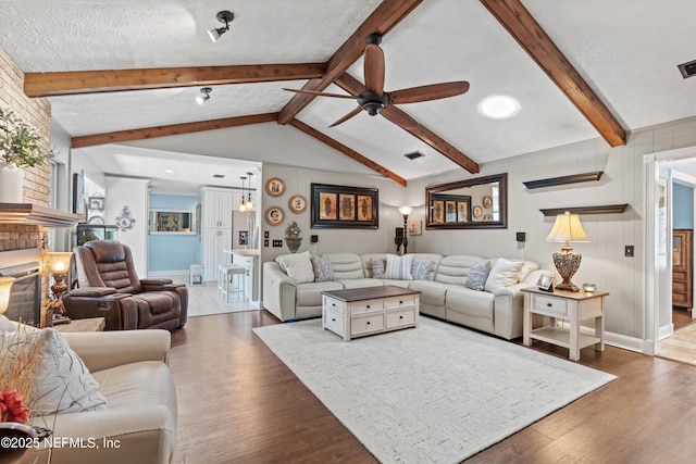 living room with dark hardwood / wood-style flooring, a textured ceiling, and vaulted ceiling with beams