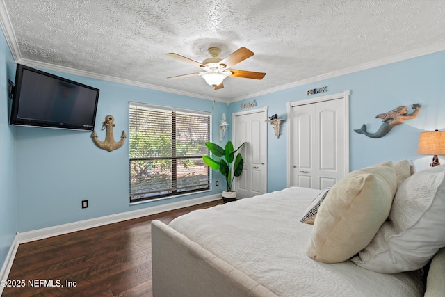 bedroom with dark hardwood / wood-style floors, ceiling fan, multiple closets, crown molding, and a textured ceiling