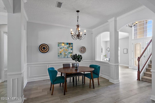 dining area with a textured ceiling, ornamental molding, and a notable chandelier