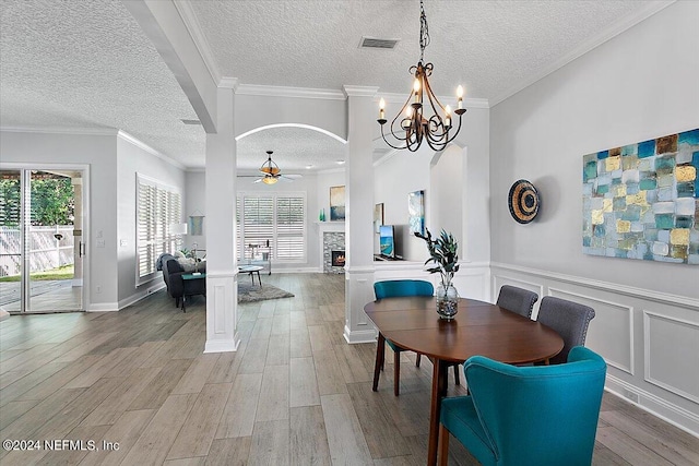 dining area with ceiling fan with notable chandelier, a textured ceiling, hardwood / wood-style flooring, and ornamental molding