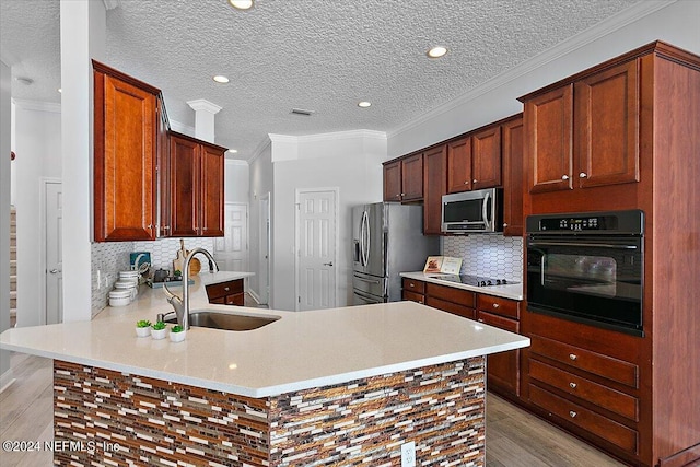 kitchen with black appliances, kitchen peninsula, sink, and crown molding