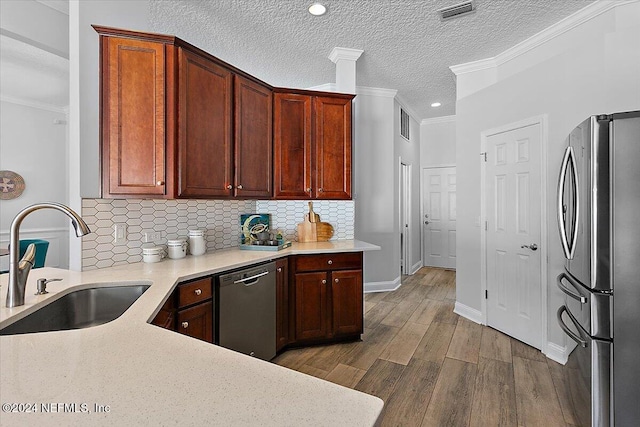 kitchen featuring sink, ornamental molding, stainless steel appliances, a textured ceiling, and dark hardwood / wood-style flooring