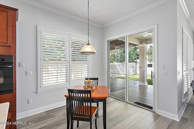 dining room featuring a textured ceiling, light hardwood / wood-style flooring, and ornamental molding