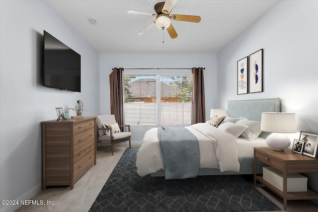 carpeted bedroom featuring ceiling fan and a textured ceiling