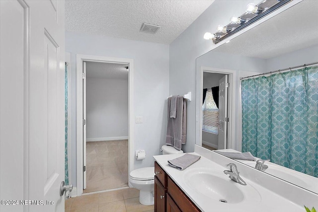 bathroom featuring a textured ceiling, toilet, tile patterned flooring, and vanity