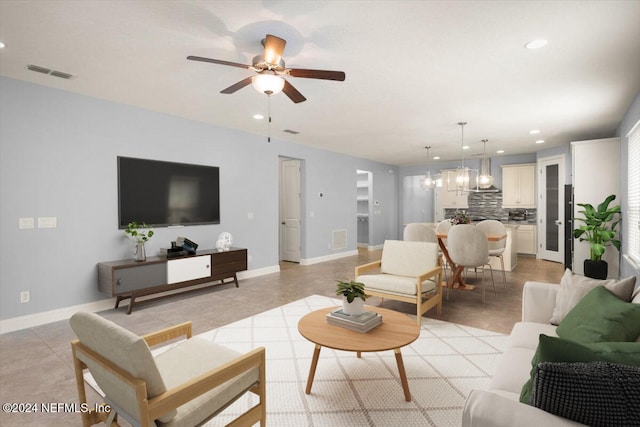 tiled living room featuring ceiling fan with notable chandelier