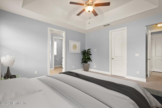 carpeted bedroom featuring ceiling fan and a raised ceiling