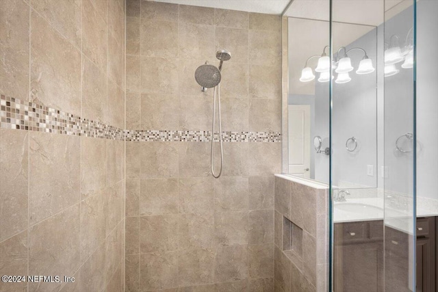 bathroom with tiled shower and vanity