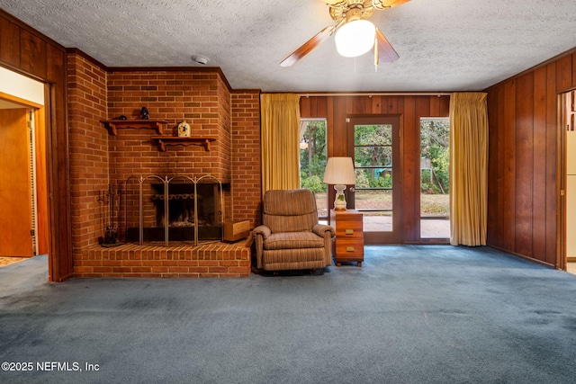 living room featuring carpet floors, a textured ceiling, wood walls, and a fireplace