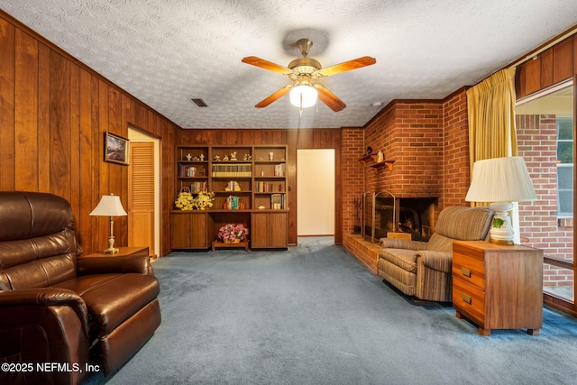 living area featuring carpet, a textured ceiling, a fireplace, and wooden walls