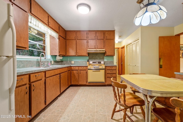 kitchen featuring a textured ceiling, range, white fridge, decorative backsplash, and sink