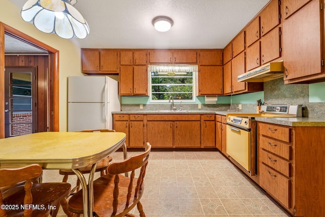 kitchen with sink, white refrigerator, a textured ceiling, and range