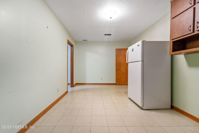 kitchen featuring white refrigerator and a textured ceiling