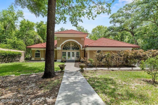 mediterranean / spanish-style home featuring a front yard and french doors