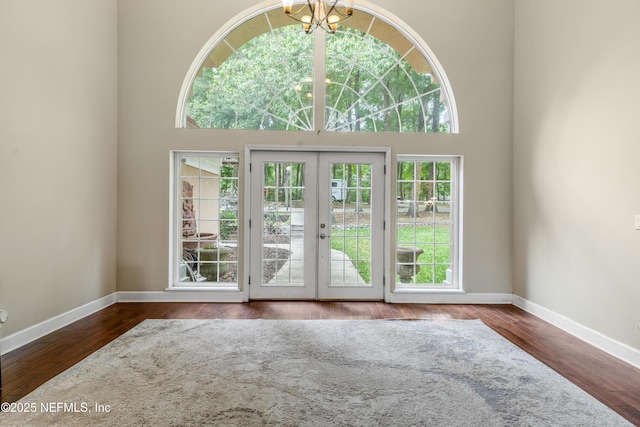 doorway with an inviting chandelier, a towering ceiling, french doors, and hardwood / wood-style flooring