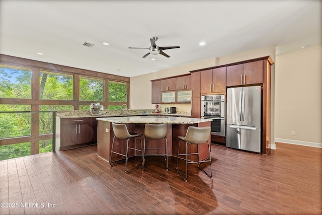 kitchen featuring sink, a center island, appliances with stainless steel finishes, dark hardwood / wood-style floors, and ceiling fan