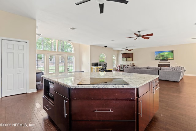 kitchen featuring french doors, dark wood-type flooring, a kitchen island, light stone countertops, and black appliances