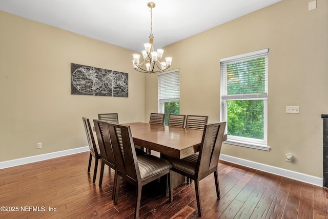 dining room with a healthy amount of sunlight, wood-type flooring, and a notable chandelier