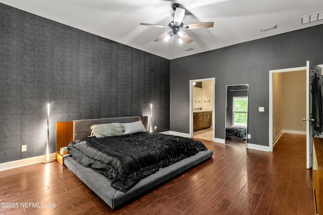 bedroom with wood-type flooring, ceiling fan, and ensuite bath