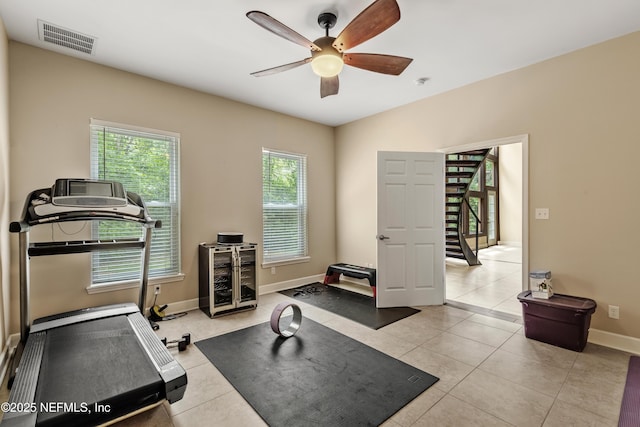 exercise room with light tile patterned floors and ceiling fan