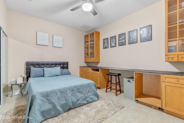 tiled bedroom featuring built in desk and ceiling fan